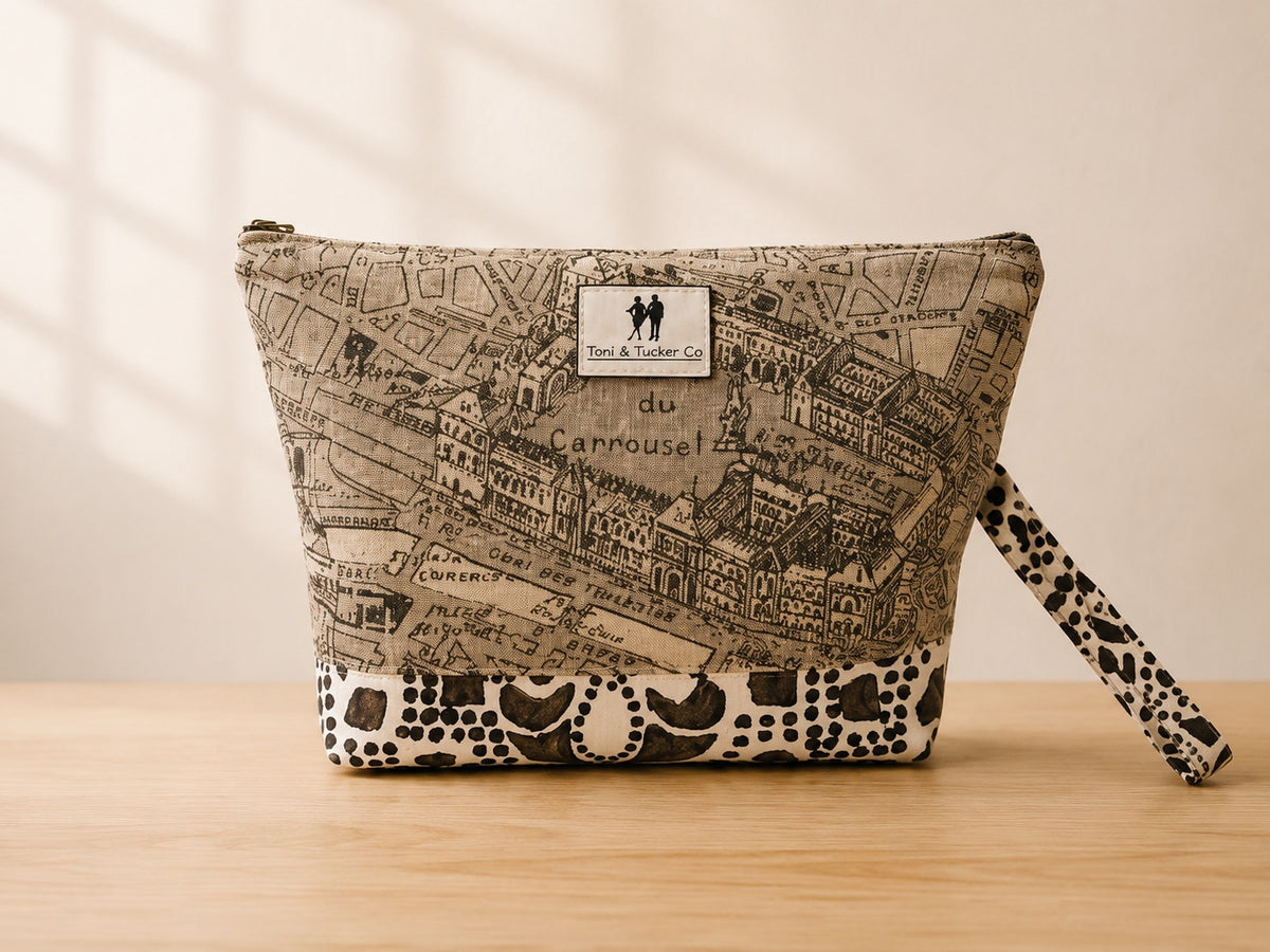 Front view of NO.001 Studio Pouch – Paris Atelier with vintage map textile, black and ivory dot motif, exterior Toni & Tucker label, and wrist strap.