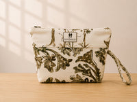 Front view of NO.002 Studio Pouch – Olive Grove with olive botanical textile, cream upper panel, exterior Toni & Tucker label, and wrist strap.