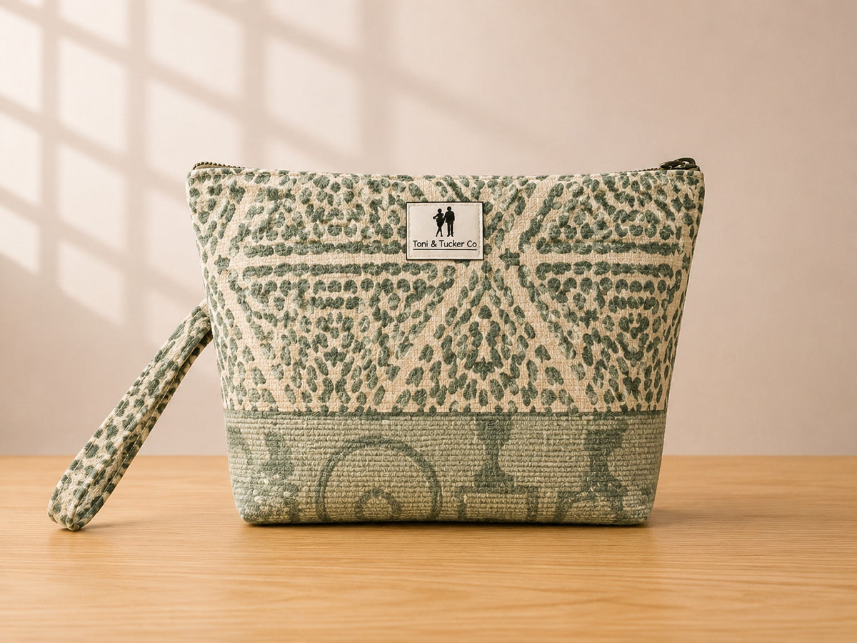 Front view of NO.003 Studio Pouch – Sage Lattice with sage geometric textile, tonal base panel, exterior Toni & Tucker label, and wrist strap.