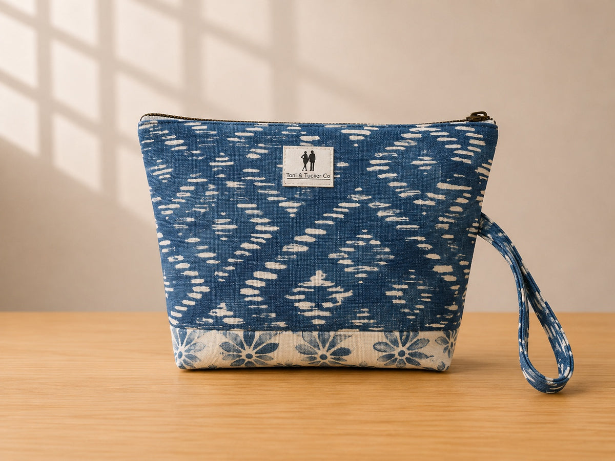 Front view of NO.005 Studio Pouch – Indigo Ikat with blue patterned textile, exterior Toni and Tucker label, zipper closure, and wrist strap.