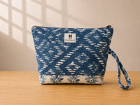 Front view of NO.005 Studio Pouch – Indigo Ikat with blue patterned textile, exterior Toni and Tucker label, zipper closure, and wrist strap.