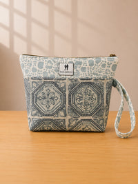 Front view of NO.007 Studio Pouch – Blue Courtyard with blue courtyard-inspired textile, exterior Toni and Tucker label, zipper closure, and wrist strap.