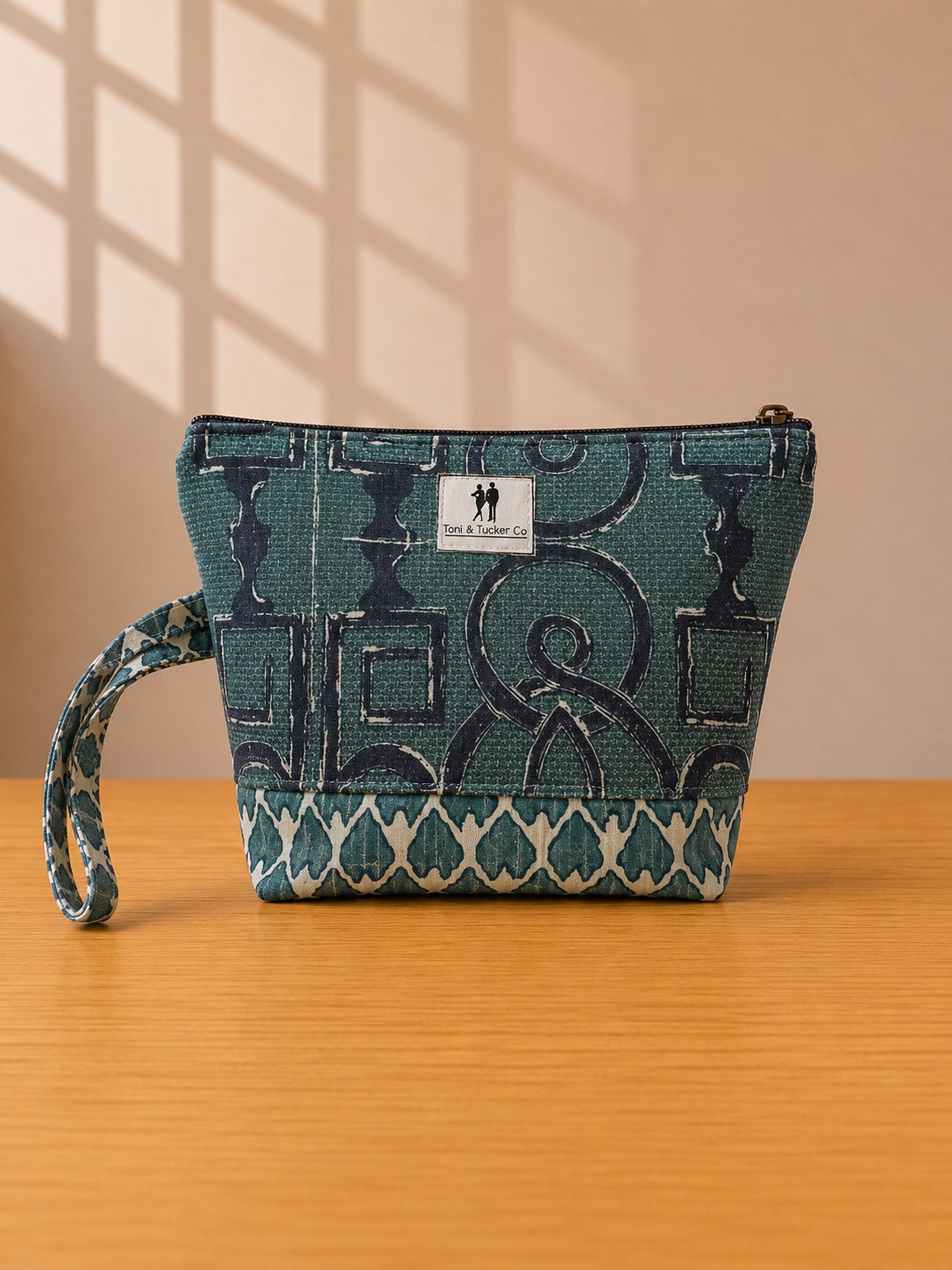 Front view of NO.008 Studio Pouch Deep Harbor with deep blue patterned textile, label, zipper closure, and wrist strap.