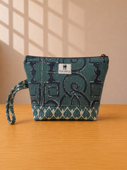 Front view of NO.008 Studio Pouch Deep Harbor with deep blue patterned textile, label, zipper closure, and wrist strap.