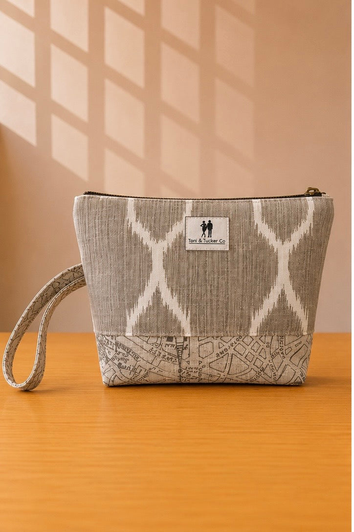 Front view of NO.009 Studio Pouch Sandstone Key with neutral patterned fabric, label, zipper closure, and wrist strap.