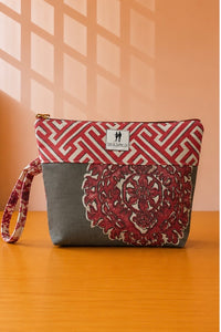 Front view of NO.010 Studio Pouch Terracotta Fern with red and gray patterned fabric, label, zipper closure, and wrist strap.