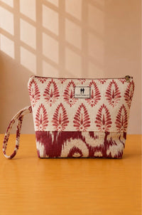 Front view of NO.013 Studio Pouch – Crimson Bazaar with cream and red patterned textile, exterior Toni & Tucker label, zipper closure, and wrist strap.